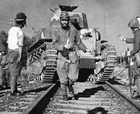 Командир японского танка ведет средний танк типа 89 на железнодорожном переезде. Китай, 1938 г.