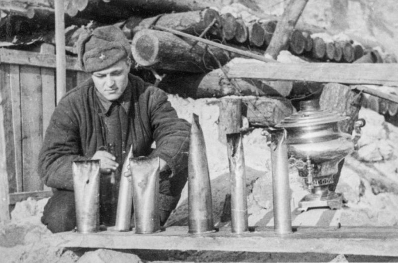 Красноармеец чистит и заправляет самодельные блиндажные светильники-коптилки. Сталинград, 1942 г.