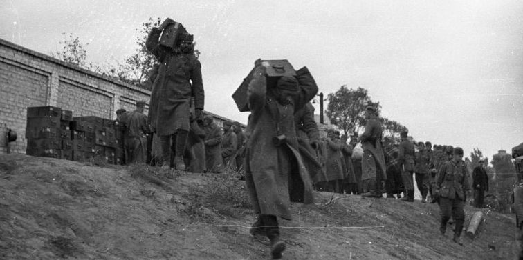 Советские пленные солдаты под конвоем немцев переносят ящики в Днепропетровске. 1941 г. 