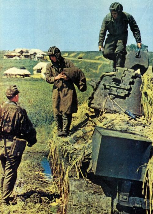 Экипаж завязшего в грязи советского танка Т-34 сдается в плен эсэсовцу. 1943 г.