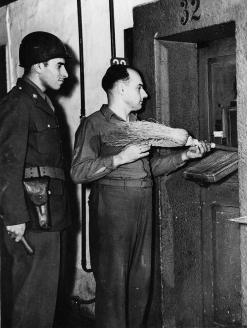 Передача заключенному метлы для подметания его камеры. 1945 г.