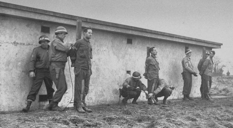 Американские военные полицейские привязывают к столбу немецких диверсантов перед расстрелом. Декабрь 1944 г.