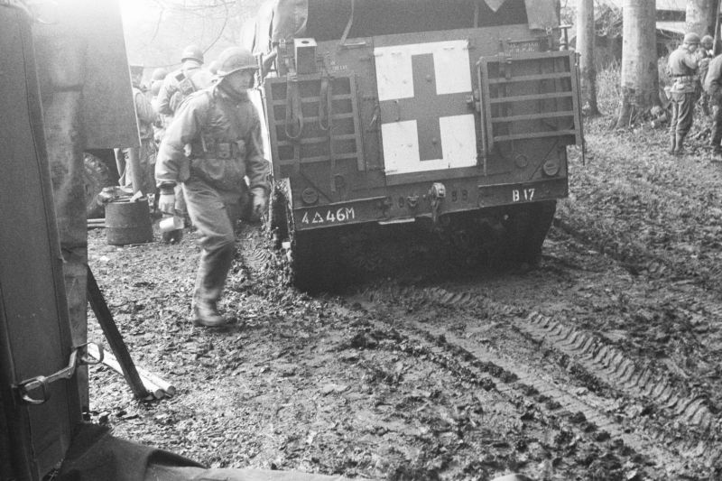 Солдаты и санитарный бронетранспортер М3А1 4-й бронетанковой дивизии США у полевого госпиталя бельгийского местечка Ассенуа. Декабрь 1944 г.