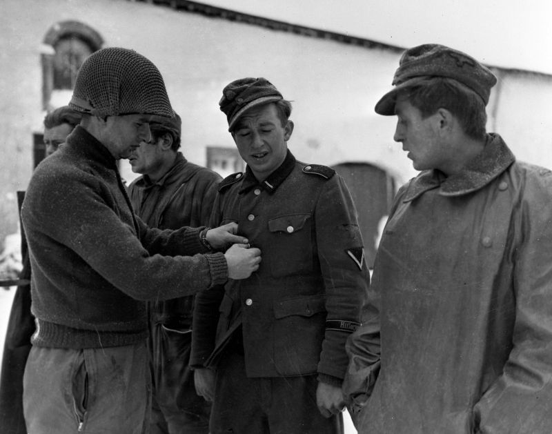 Американский солдат обыскивает военнопленных из 12-й танковой дивизии СС «Гитлерюгенд». Январь 1945 г.