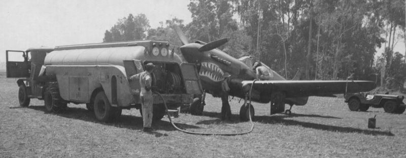 Топливозаправщик Autocar U7144T заправляет истребитель Р-40 7-й истребительной авиагруппы ВВС США на аэродроме близ Дободура. 1943 г. 