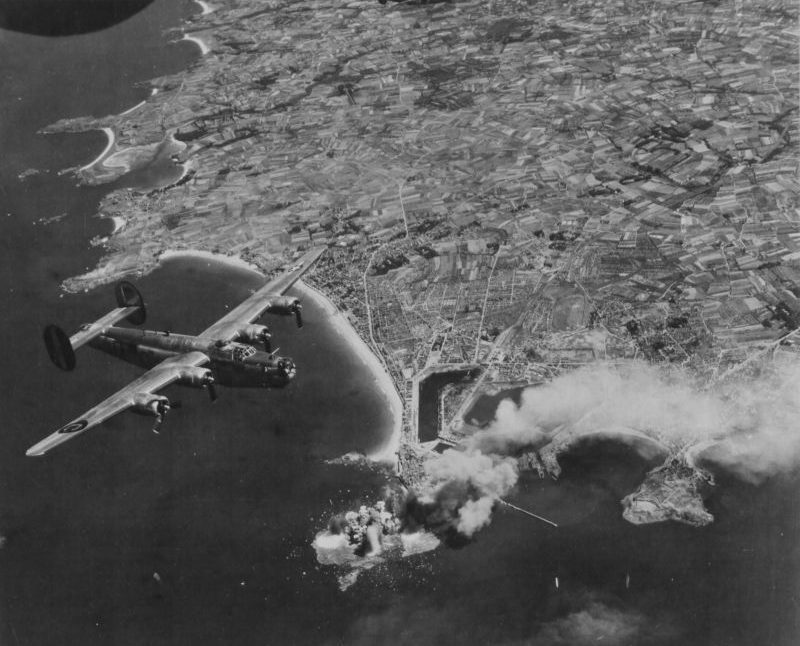 Бомбардировщик В-24 «Либерейтор» в полете над горящим французским городком Сен-Мало. 1944 г.