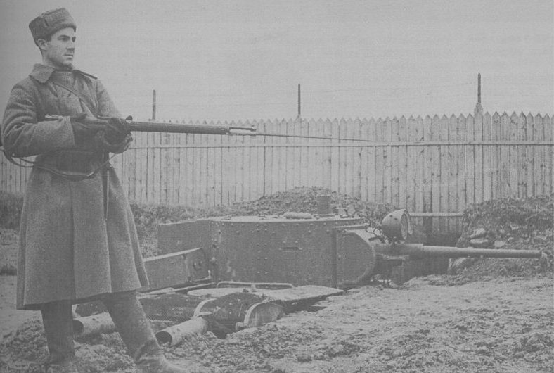 Неисправный танк БТ-5, врытый в землю в пригороде Москвы, и боец народного ополчения. Октябрь 1941 г.