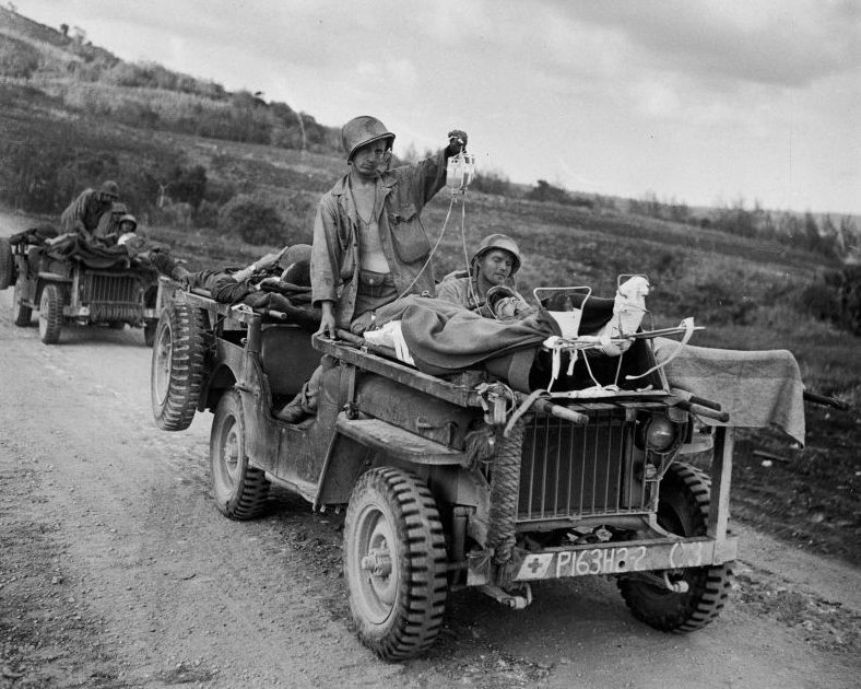 Перевозка раненых американских солдат на армейских автомобилях во время боев за Сайпан. Июнь 1944 г. 