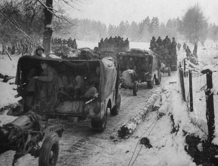 Колонна автомобилей «Додж WC51/52» с прицепленными легкими полевыми 75-мм гаубицами М1 на дороге в Арденнах. Декабрь 1944 г. 