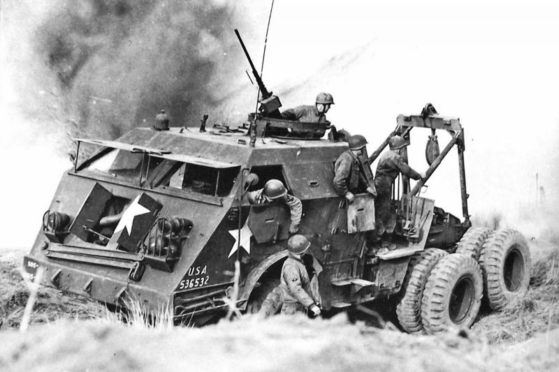 Экипаж американской БРЭМ M26 «Dragon Wagon» под артобстрелом пытается эвакуировать поврежденный танк М4 «Шерман». 1944 г. 