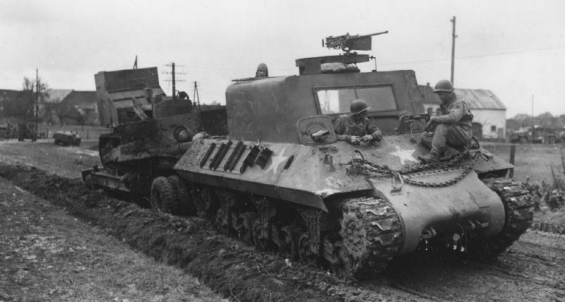 Артиллерийский тягач M35 с бульдозером D7 на прицепе в населенном пункте Кильбургвайлер, Германия. Март 1945 г. 