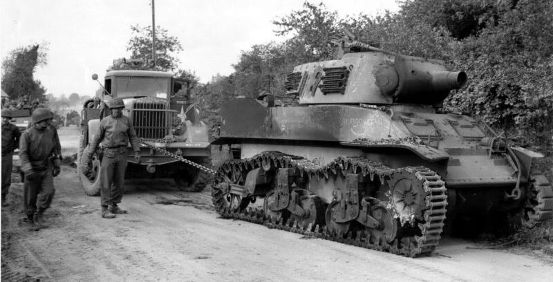 Ремонтно-эвакуационная машина Kenworth M1 стягивают с дороги уничтоженную 75-мм самоходную гаубицу M8. 1945 г. 