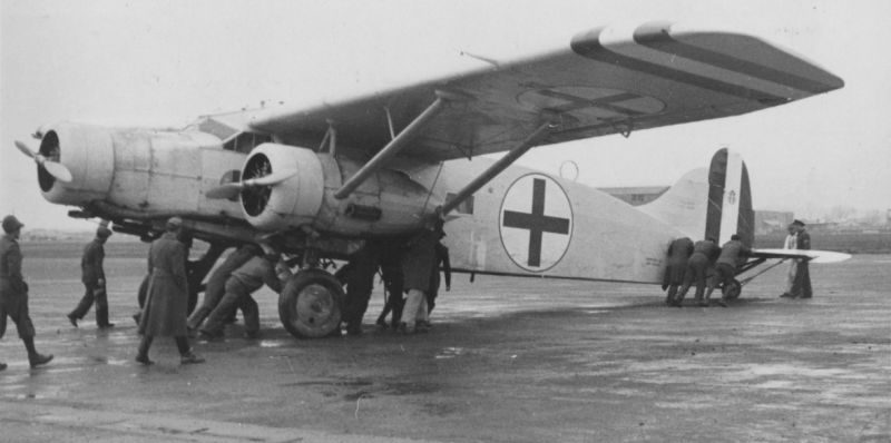 Аэродромный персонал откатывает на стоянку санитарный самолет Caproni Ca.133. 1941 г. 