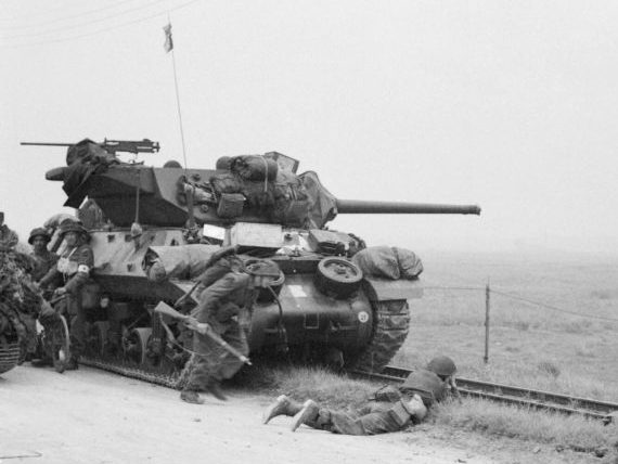 САУ М10 прикрывает солдат, развивающих наступление в районе высадки «Суод» в Нормандии. 6 июня 1944 г.