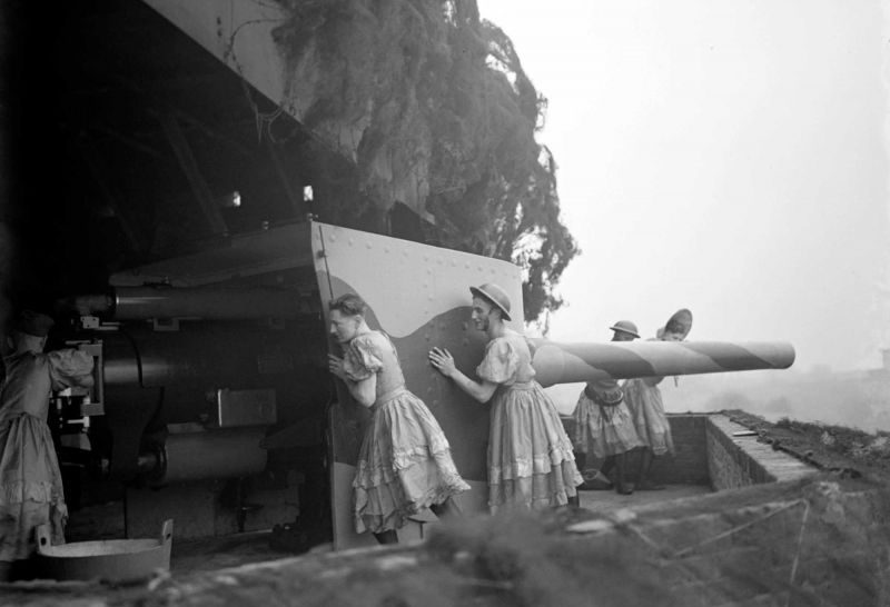 Британские артиллеристы разворачивают 6-дюймовое орудие во время воздушной тревоги на береговой батарее в форте Шорнмид. Солдаты на фото одеты в женские платья, поскольку в данный момент репетировали представление художественной самодеятельности. 1941 г. 
