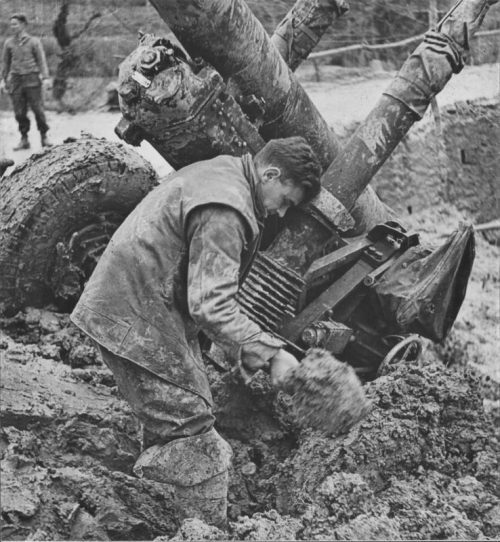 Британский артиллерист расчищает провалившуюся в грязь 4,5-дюймовую пушку. 1944 г.