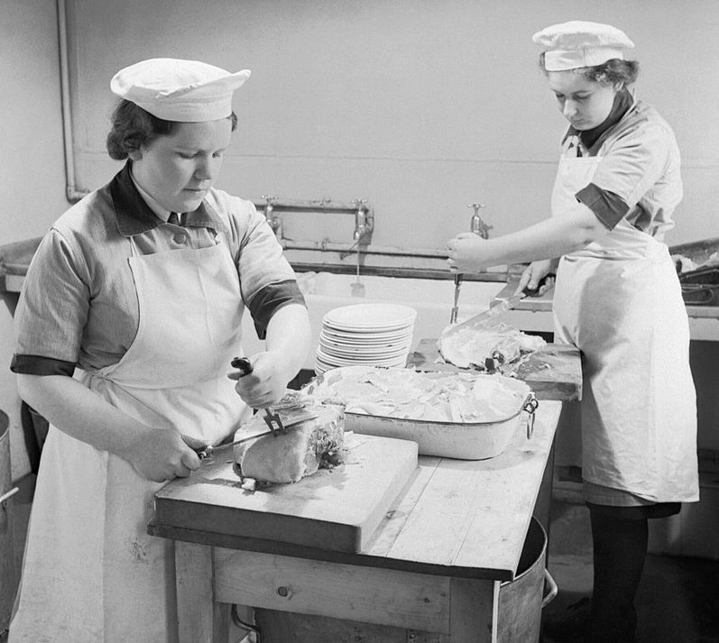 Служащие из WRNS готовят пищу на кухне военно-морской базы.