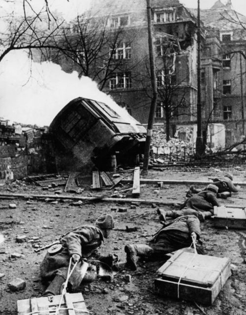 Штурмовая группа саперов тащит ящики со взрывчаткой для подрыва дома. Март 1945 г.