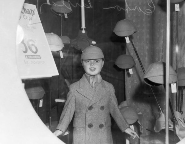 Витрина в городском магазине, показывающая ценник и количество купонов, необходимых для покупки детского пальто и шапок.