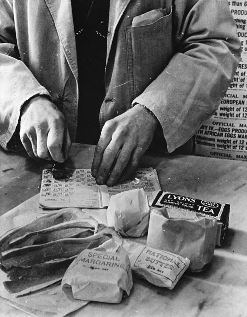 Продавец магазина «гасит» купоны в книжке британской домохозяйки в 1943 году.