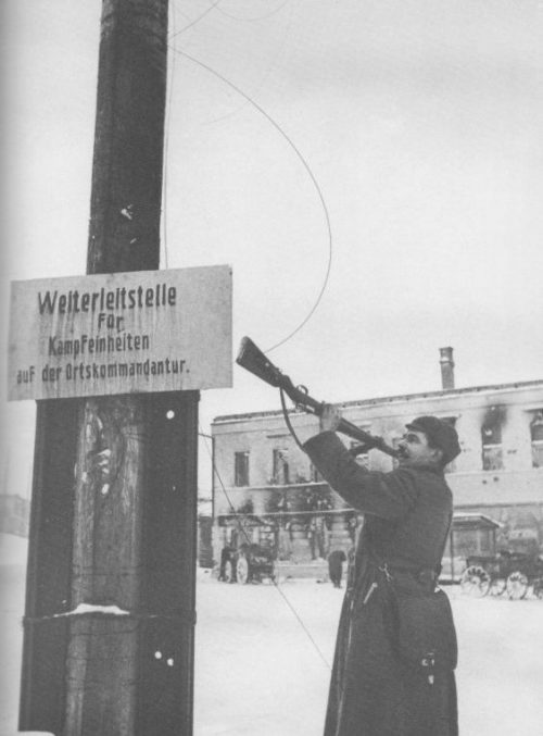 Советский боец сбивает немецкую табличку со столба в освобожденном Наро-Фоминске. Декабрь 1941 г.
