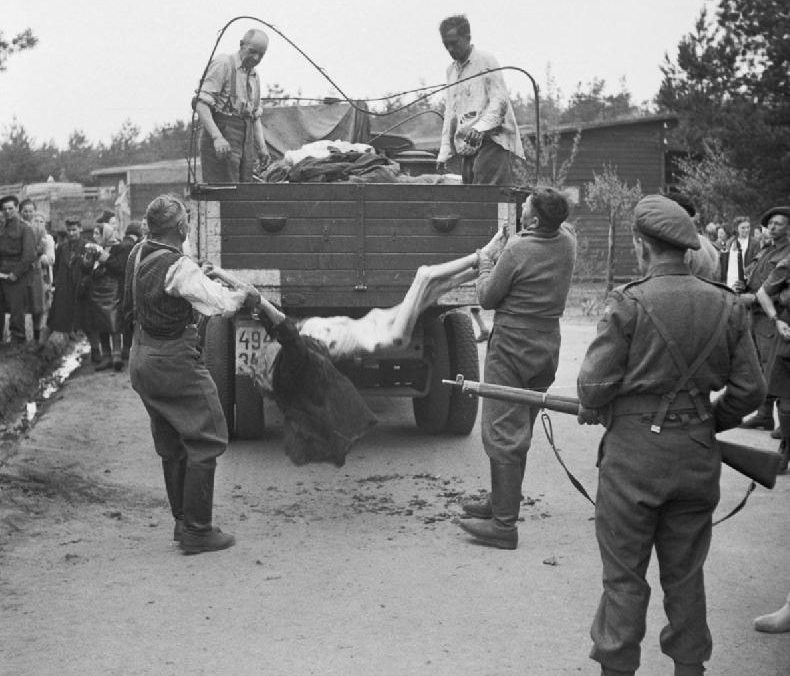Бывших охранников заставляют грузить тела погибших заключенных для захоронения. Апрель 1945 г.
