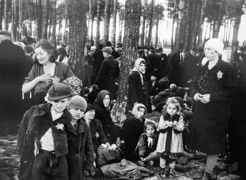 Еврейские женщины и дети в сосновой роще на территории концлагеря Освенцим в ожидании отправки в газовые камеры. 1944 г. 