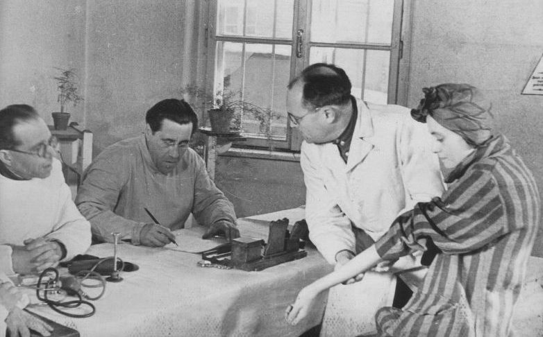 Узница концлагеря Освенцим демонстрирует советской врачебной комиссии свой личный номер, выбитый на руке. 1945 г. 