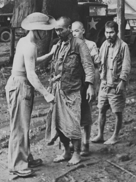 Австралийский солдат обыскивает японского пленного на Бирме. Июль 1945 г. 