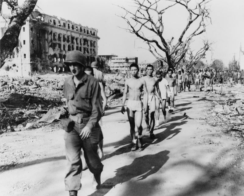 Японские пленные идут под конвоем американских солдат на Филиппинах. Июль 1945 г.