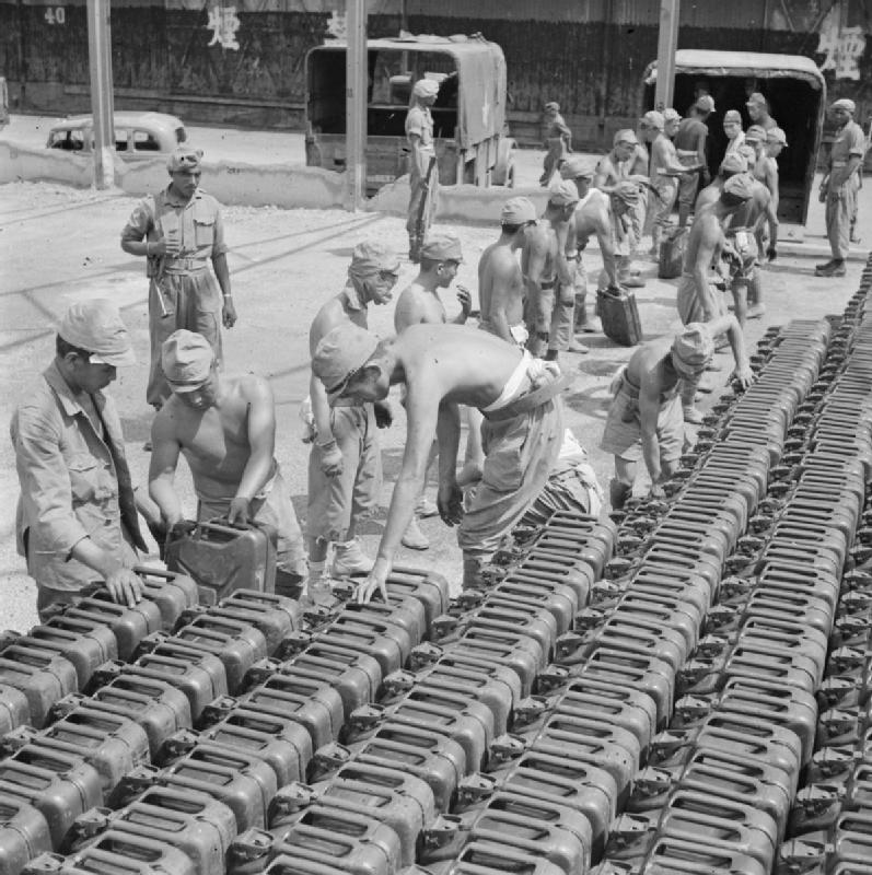 Японские военнопленные разгружают канистры с бензином в доках Сингапура. Сентябрь 1945 г.