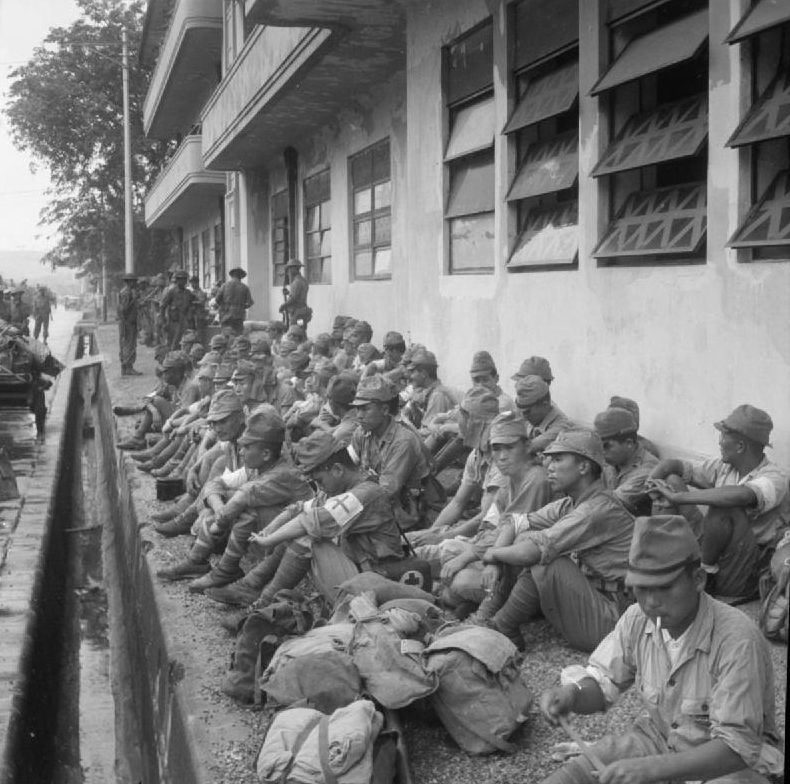 Солдат 5-й индийской дивизии охраняет японских военнопленных в Сингапуре. 1945 г. 