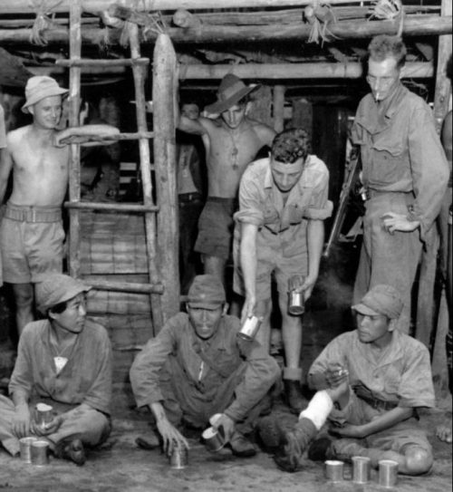Австралийские солдаты угощают японских военнопленных мясными консервами. Новая Гвинея, 1945 г.