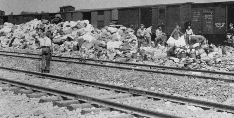 Заключенные выгружают конфискованное имущество из вагона евреев из Подкарпатской Руси на склад в концлагере Аушвиц-Биркенау. Апрель 1944 г.