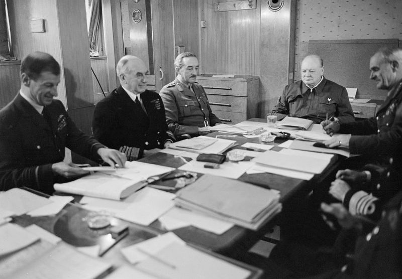 Главный маршал авиации Чарльз Портал, адмирал флота Дадли Паунд, генерал Алан Брук и Уинстон Черчилль за столом переговоров на борту RMS «Queen Mary». 1943 г.