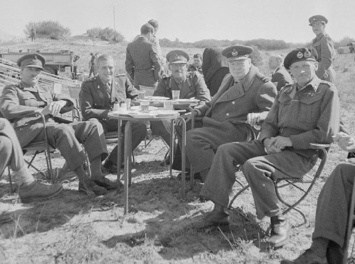 Обед на свежем воздухе премьер-министра Уинстона Черчилля вместе с генералом сэром Бернардом Монтгомери и другими старшими офицерами Восьмой армии во время визита Черчилля в Триполи. 1943 г. 