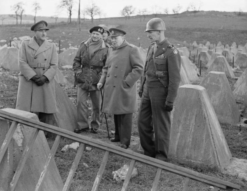 Черчилль с фельдмаршалом сэром Аланом Бруком, фельдмаршалом Монтгомери и генералом Симпсоном среди препятствий из «зубов дракона» на линии Зигфрида возле Аахена. 1945 г.