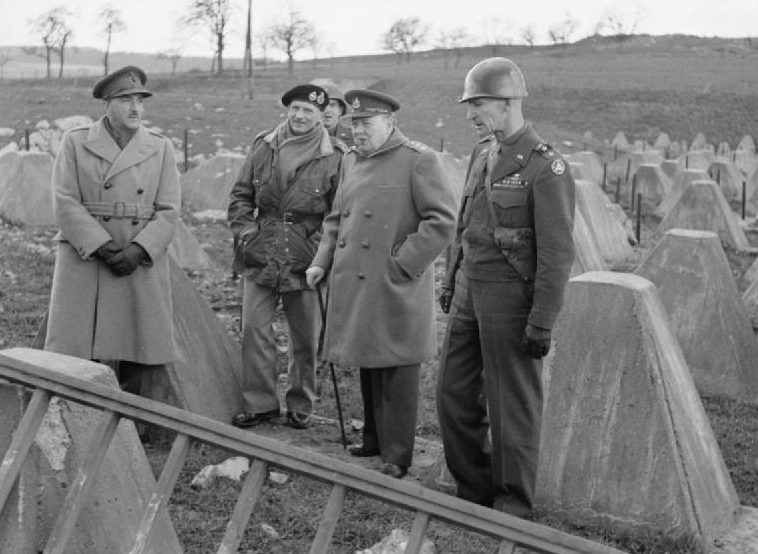 Уинстон Черчилль с фельдмаршалом Аланом Бруком, фельдмаршалом Монтгомери и генералом Симпсоном среди препятствий из «зубов дракона» на линии Зигфрида возле Аахена. 1945 г.