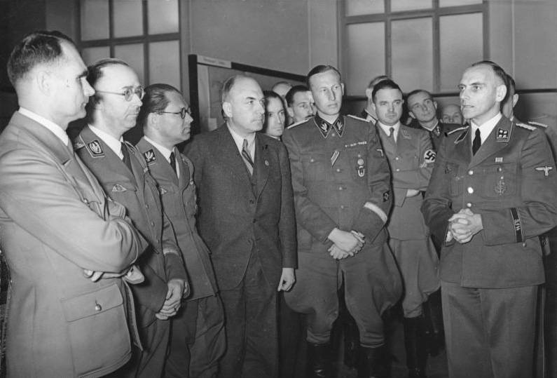 Слева направо: Рудольф Гесс, Генрих Гиммлер, Филипп Булер, Фриц Тодт и Рейнхард Гейдрих слушают Конрада Мейера на выставке «Generalplan Ost» в Берлине. 1941 г.