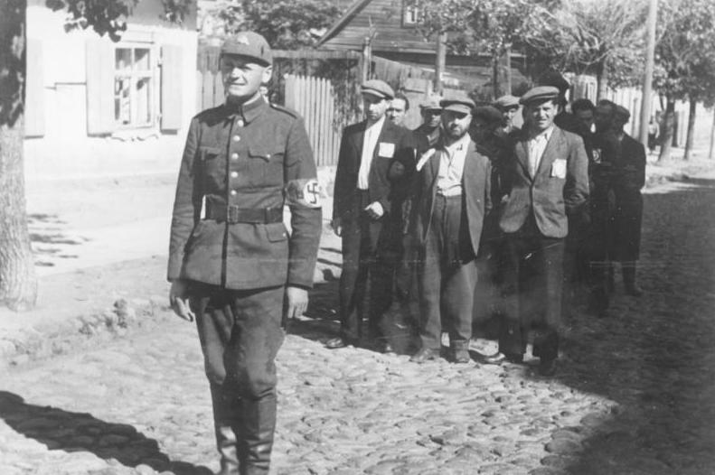 Литовский полицай сопровождает группу литовских евреев в Вильнюсе в июле 1941 г.