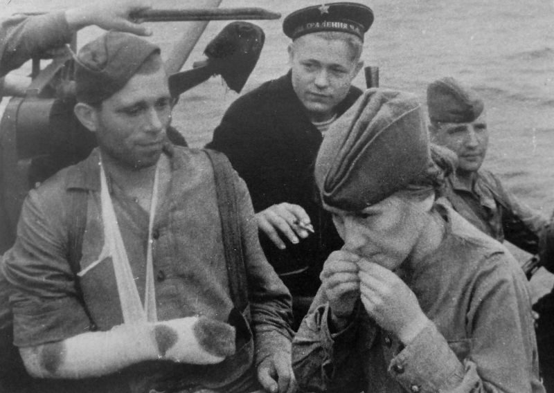 Военнослужащая РККА склеивает цигарку раненому бойцу во время эвакуации по Черному морю. 1941 г. 