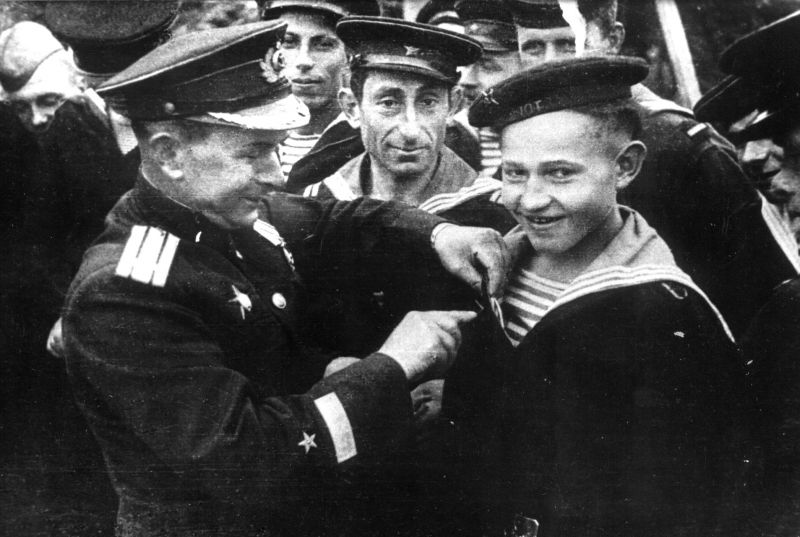Командир бригады торпедных катеров Северного флота А.В. Кузьмин вручает юнге Саше Ковалеву орден Красной Звезды. 1944 г. 
