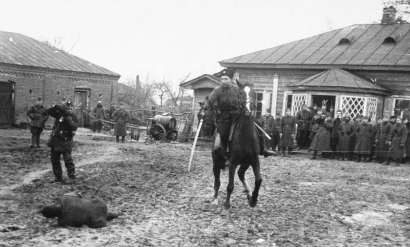 Казак-полицай рубит шашкой пленных советских партизан. Ноябрь 1941 г. 