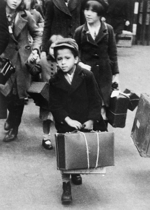 Чернокожий маленький мальчик во время отъезда из Лондона с другими эвакуируемыми. Июль 1940 г.