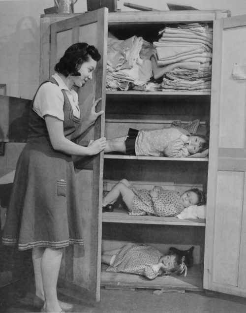 Воспитательница яслей укрывает детей в шкафу во время авианалета на Лондон. 1940 г.