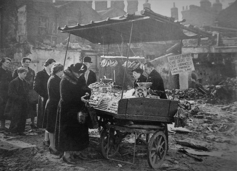 Продажа фруктов рядом с разрушенным немецкими авиабомбами зданием на улице Лондона. 1940 г. 