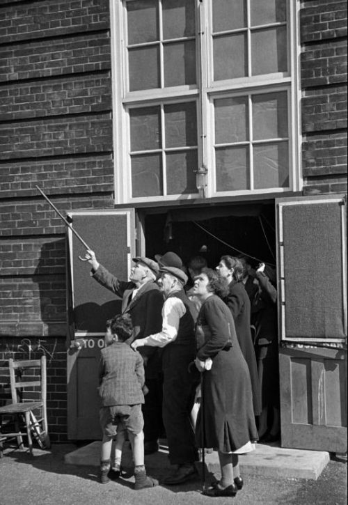 Жители Лондона наблюдают за немецкими самолетами у входа в бомбоубежище. 1940 г.