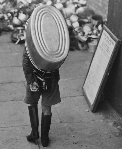 Мальчик несет ванну на пункт сбора изделий из алюминия в британском городе. 1941 г.