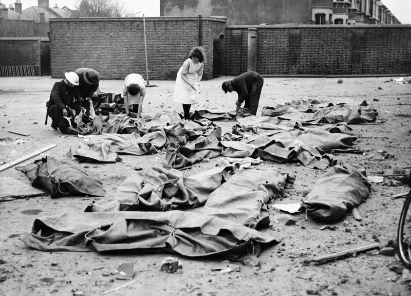 Наблюдатели МПВО и медсёстры накрывают тела учащихся школы на Ардгоуан-Роуд, погибших под бомбардировкой. Январь 1943 г. 