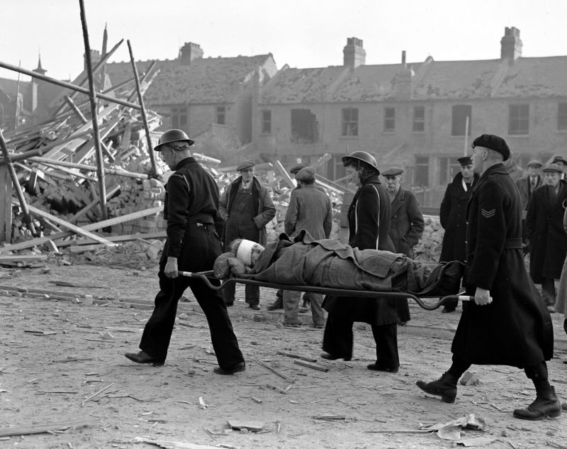Спасатели несут на носилках женщину, раненную во время авианалета на Лондон. Март 1943 г. 